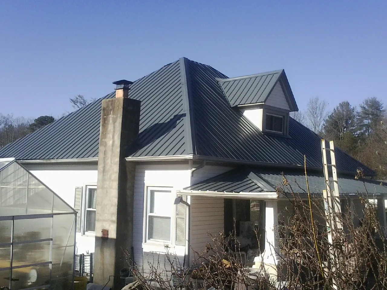 Dark blue standing seam metal roof on a white farmhouse with dormer — Slate & Tile Roof Repair by Roofing Brothers in Mulga
