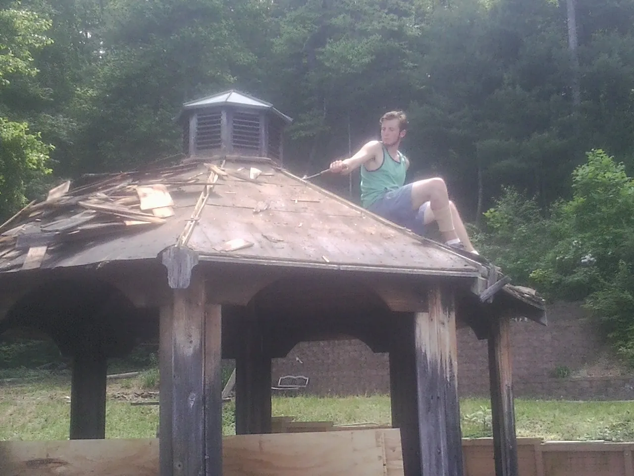 Tearing the old roof off a wooden gazebo before new shakes in Mulga