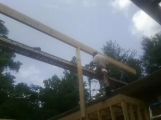 Carpenter setting a ridge beam over a new addition frame — Ice Dam Removal by Roofing Brothers in Mulga