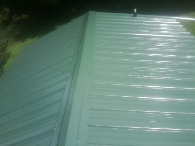 New green metal panels meeting at the ridge of a roof — Flat Roof Repair work by our crew in Mulga