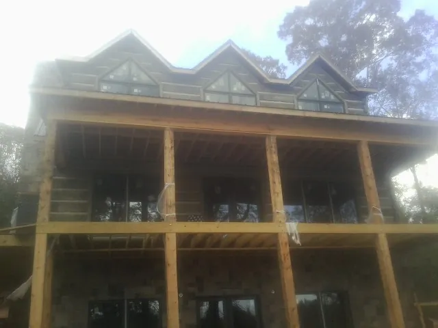 Dormers and porch framing on a large log home under construction — Roof Coating work by our crew in Mulga