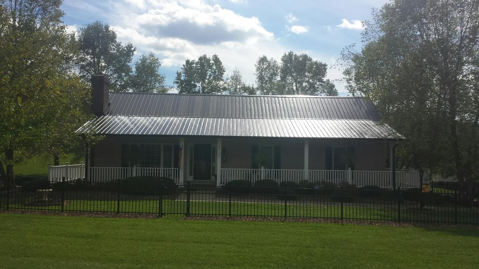 Gray metal roof on a brick ranch with a full width front porch — Gutter Guard Installation work by our crew in Mulga