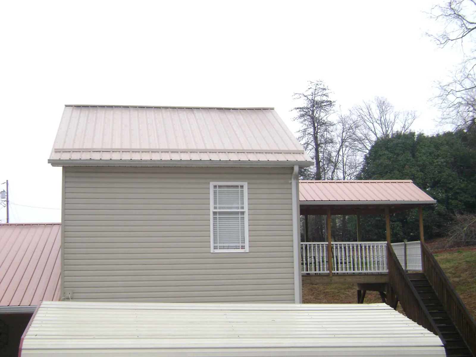Tan metal roofs on a two story addition and attached porch, from a Roof Replacement job in Mulga